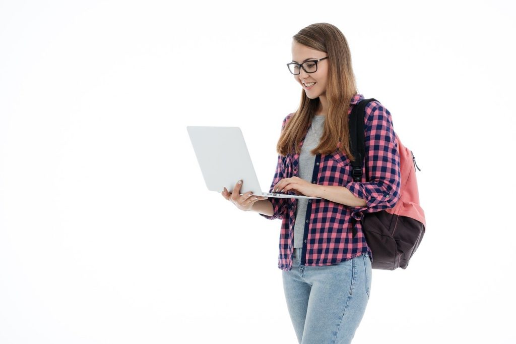 estudante em pé mexendo no computador: como funciona o ganhe bolsa